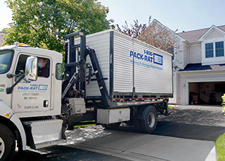 A 1-800-PACK-RAT mini-mover truck drops off a portable storage container for a customer