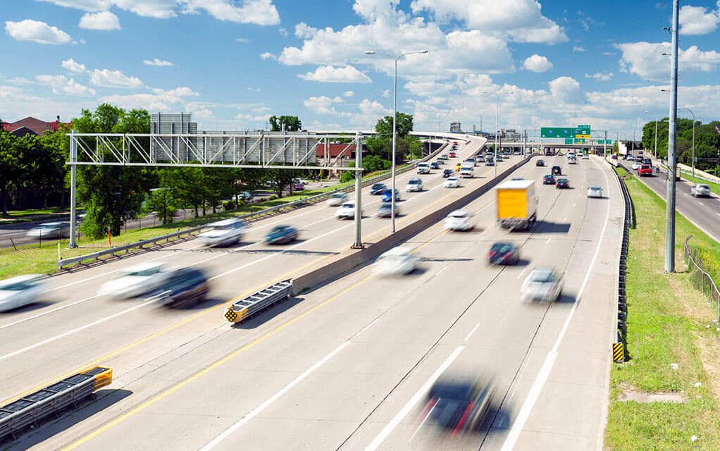 Time lapse image of a busy highway as cars and trucks travel in both directions on a partly cloudy day