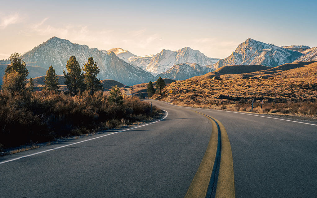 Shot of a desolate road leading into the mountains in the early morning on a bright and sunny day