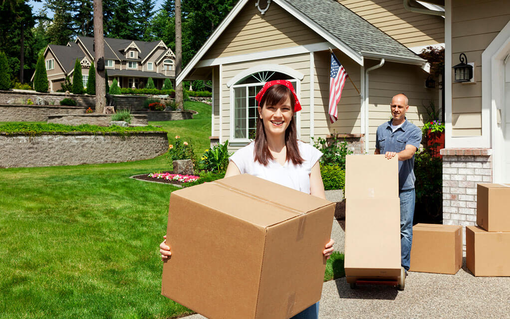A couple helps move their stuff out of their house on a bright sunny day in a nice suburban neighborhood