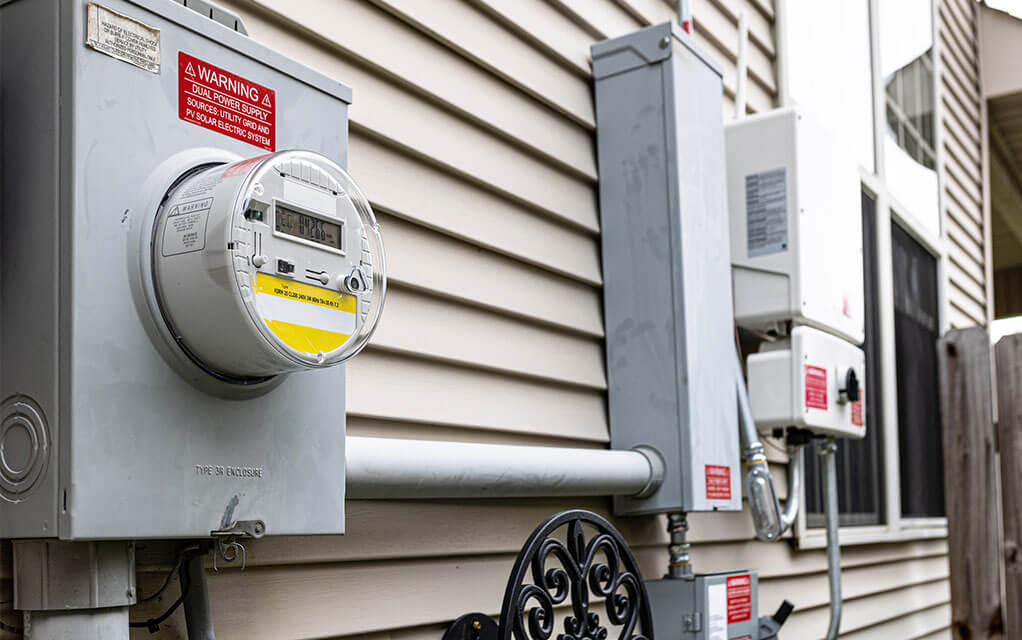 A view of outside utilities and an electric counter box on the side of a house on a cloudy day