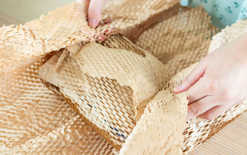 Someone packs away an item into a box using eco-friendly packing wrap