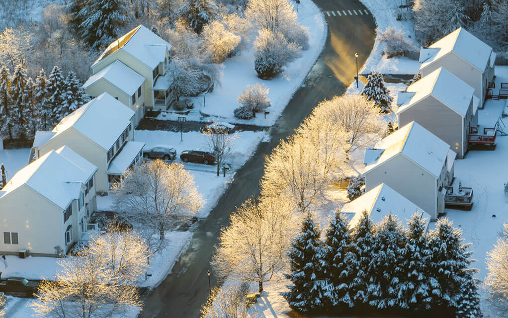 Overhead view at sunrise of a neighborhood as homes below are covered in snow
