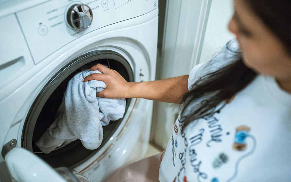 A woman loads dirty clothes into her her home's washing machine