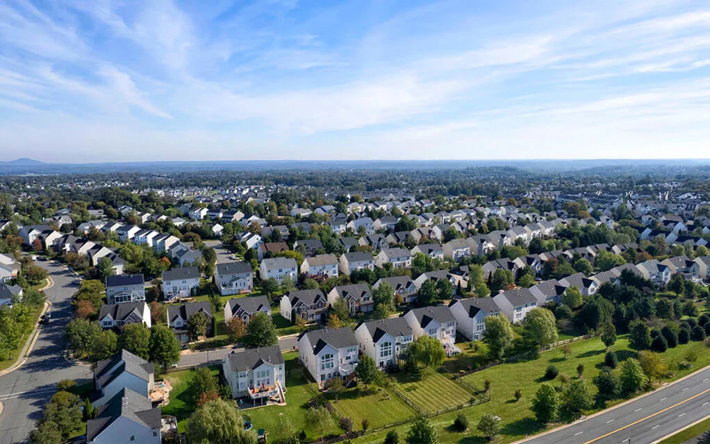 Aerial view of a large neighborhood with numerous houses in it on a mostly sunny spring day