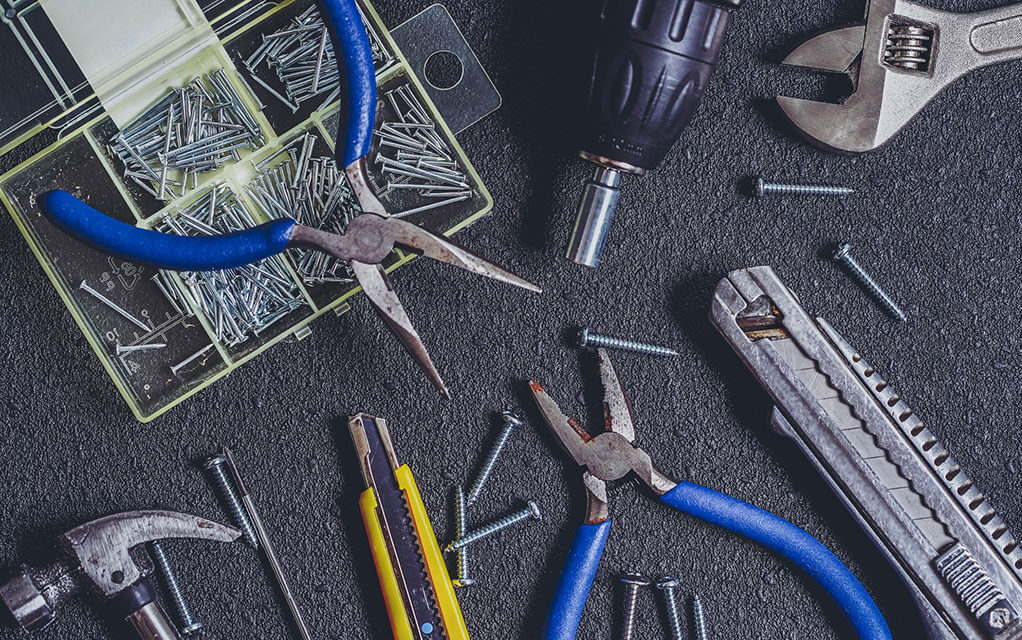 Pliers, nails, wrenches, and other tools sit arrayed on a desktop