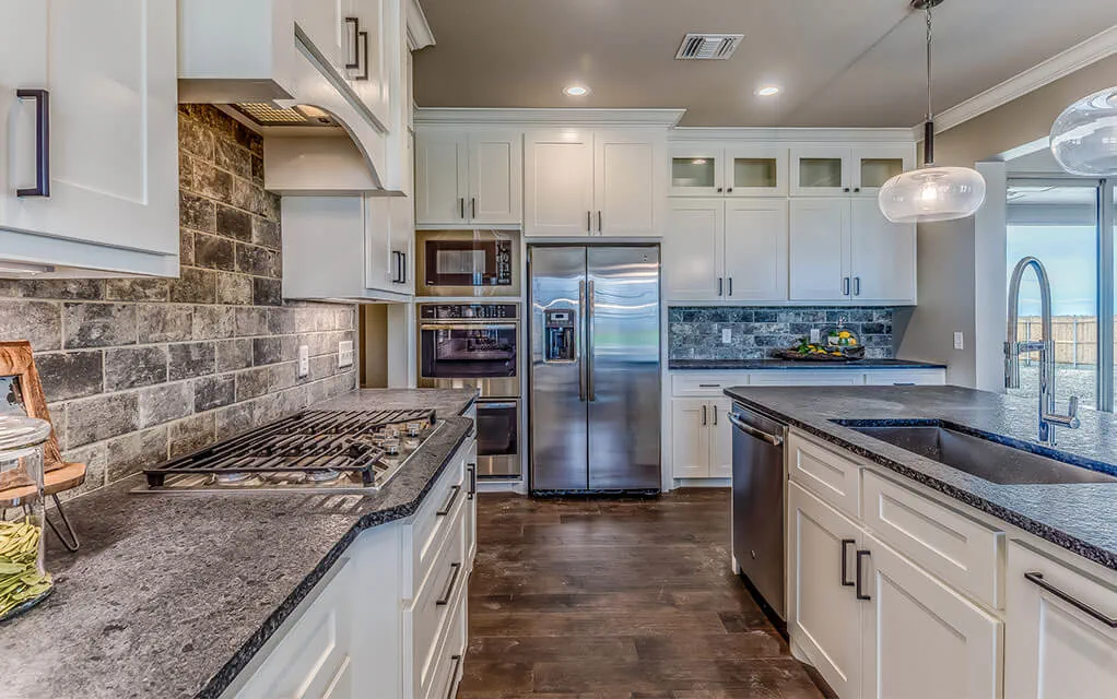 View of the inside of a home's upscale kitchen, with the refrigerator in the background
