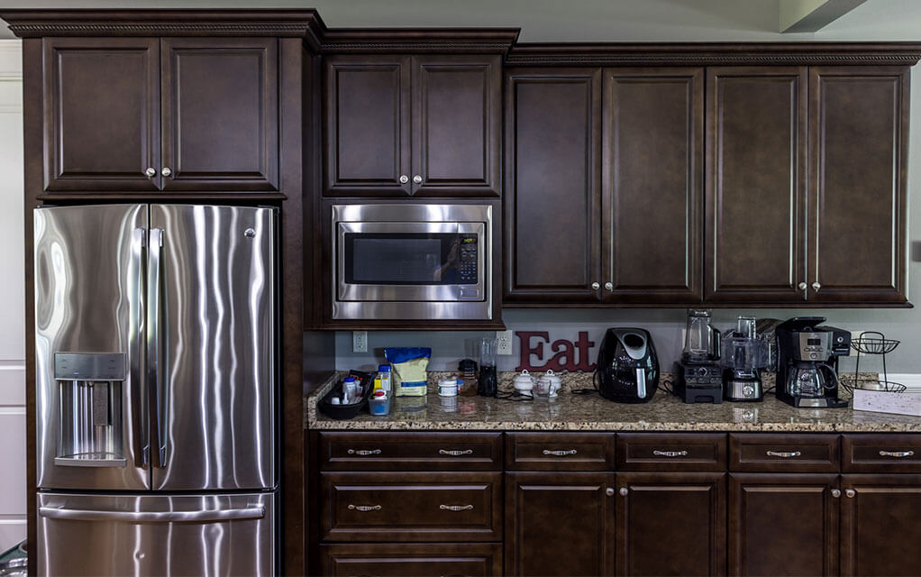 View of a kitchen's fridge with the microwave and other appliances on the counter