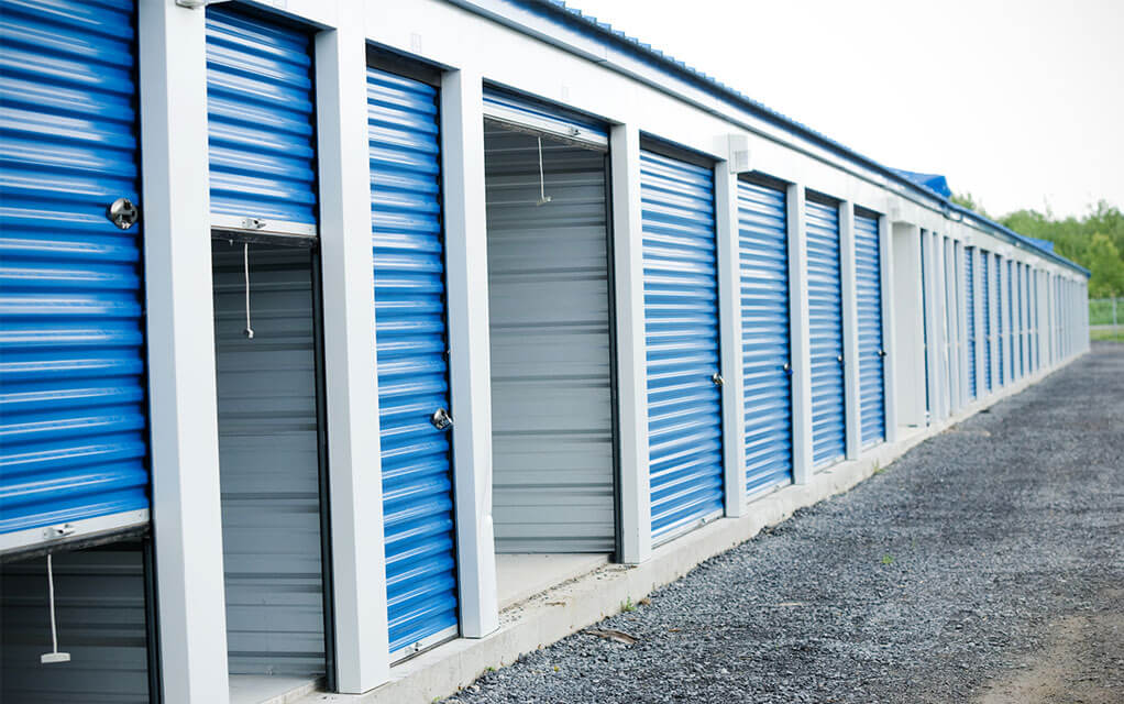 View of a line of open and closed self-storage units at an outdoor self-storage facility on a cloudy day