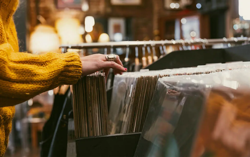 A woman looks through a set of vinyl records in an estate sale