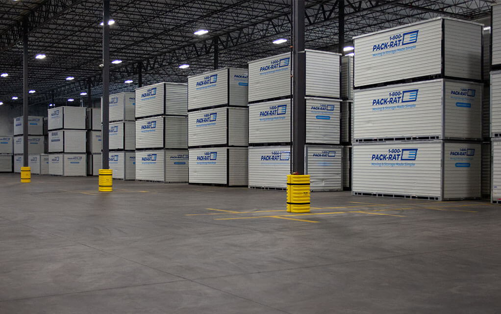 A large number of 1-800-PACK-RAT portable storage containers are securely stacked on top of each other inside of a 1-800-PACK-RAT warehouse storage location
