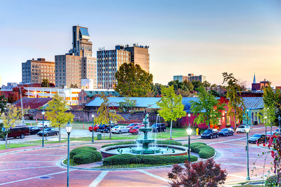 A view of the downtown August, GA cityscape with a drivable roundabout with a fountain in the center of it at twilight on a clear evening