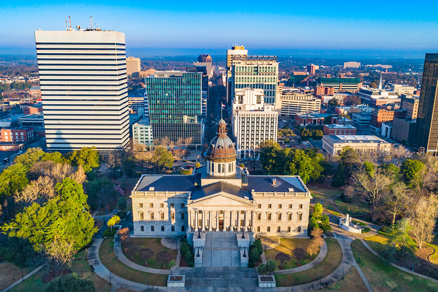 A daytime arial view of downtown Columbia, SC and the South Carolina State Capitol building as the sun rises on a clear day
